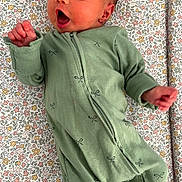 Aoife is registered to the contest to win money with this photo: baby, newborn, infant, onesie, green_clothing, floral_pattern, blanket, sleepwear, lying_down, cute, small_hands, face, mouth_open, peaceful, soft_texture, indoors, portrait, child, young_baby, cozy
