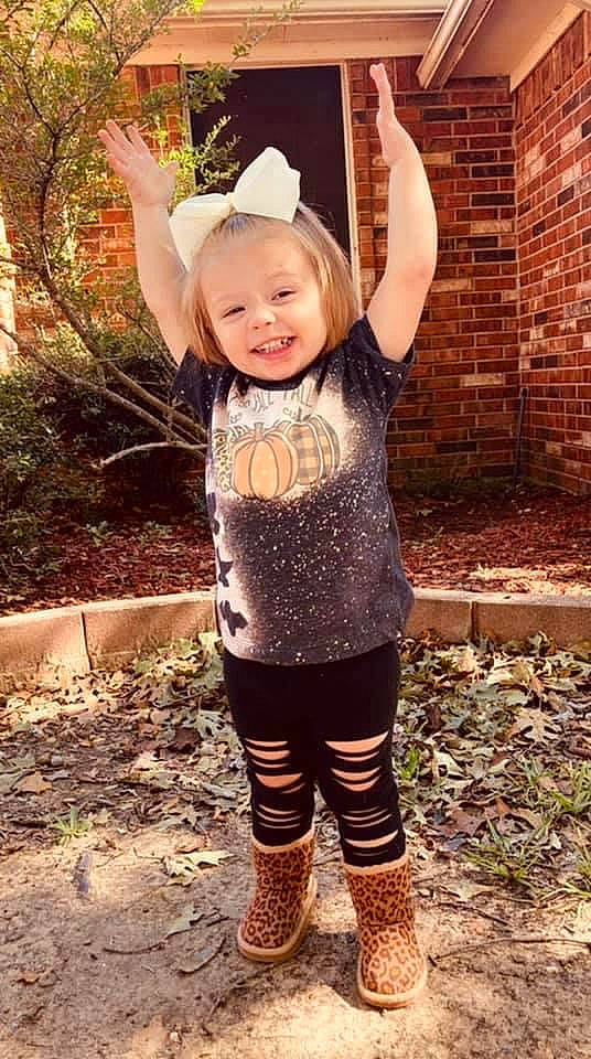 Brenley is registered to the contest to win money with this photo: baby_toddler_clothing, brick, clothing, cool, face, fun, grass, hairstyle, happy, head, human_body, joy, pattern, people_in_nature, person, pink, plant, sleeve, smile, sun_hat