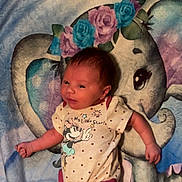 Oaklee is registered to the contest to win money with this photo: baby, infant, onesie, minnie_mouse, cartoon, elephant, blanket, flower_crown, blue, pink, polka_dots, cute, child, infant_clothing, lying_down, soft_texture, name_text, smiling, indoors, newborn