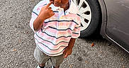 Saint is registered to the contest to win money with this photo: asphalt, boy, car, child, daylight, face, fashion, looking_down, outdoor, parking_lot, polo_shirt, portrait, shorts, sneakers, standing, street, striped_shirt, thoughtful, toddler, vehicle