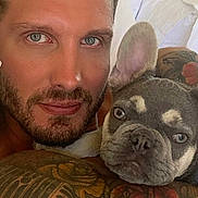 Mik joined the competition — help win amazing prizes! man, dog, french_bulldog, puppy, tattoo, rose_tattoo, face, blue_eyes, beard, arm, bed, white_sheets, indoor, portrait, close_up, cuddle, pet, skin, expression, casual