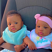 Loyalty is registered to the contest to win money with this photo: baby, infant, car_seat, seat_belt, bib, headband, pink_clothing, blue_clothing, child, toddler, cute, sitting, indoors, safety, car_interior, hand_holding, expression, portrait, two_children, young