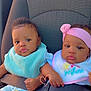 baby, infant, car_seat, seat_belt, bib, headband, pink_clothing, blue_clothing, child, toddler, cute, sitting, indoors, safety, car_interior, hand_holding, expression, portrait, two_children, young