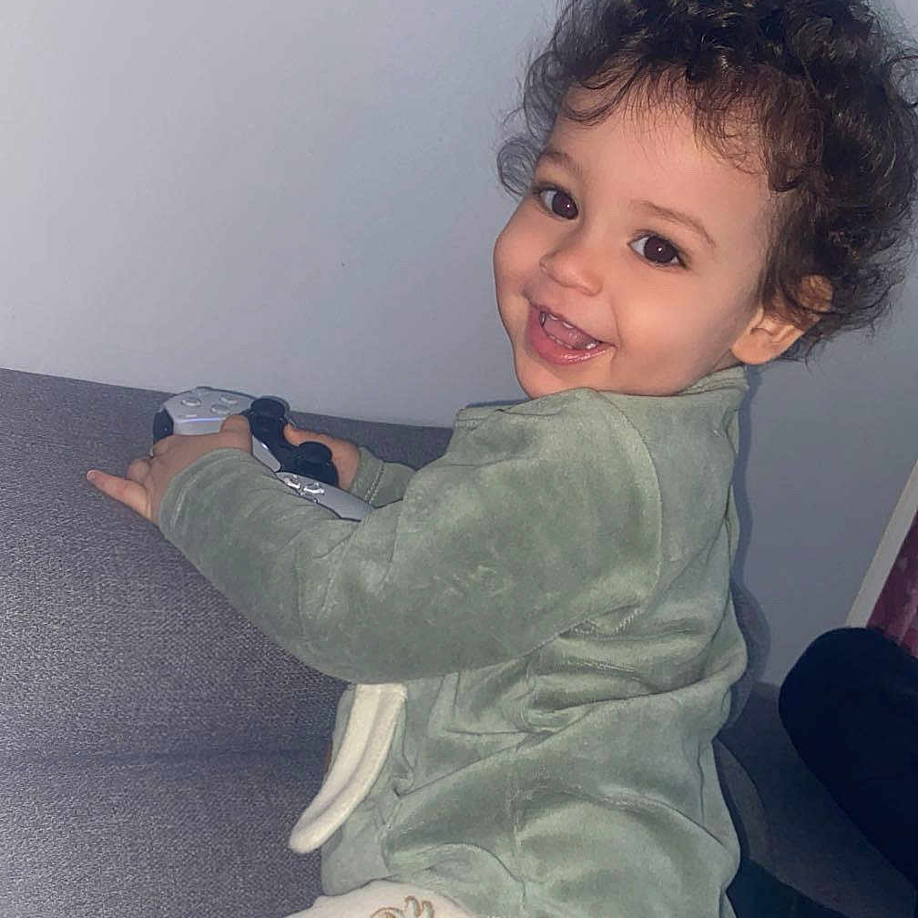 Zaïm a rejoint le concours — aidez-le/la à gagner de superbes lots ! child, clothing, couch, curly_hair, cute, dog_pattern, face, furniture, game_controller, happy, home, indoor, pajamas, person, playful, portrait, relaxed, smiling, toddler, young_child