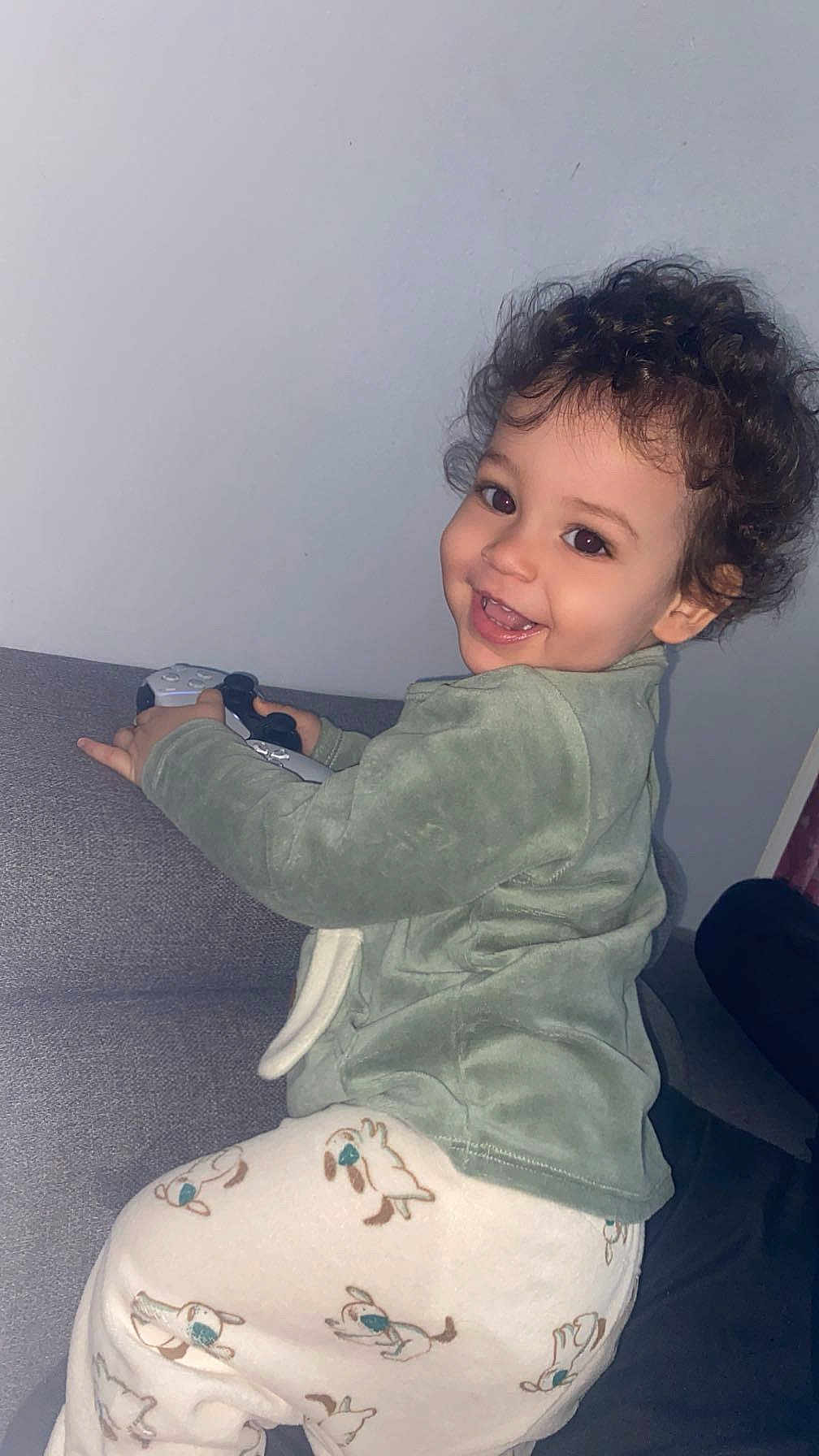 Zaïm a rejoint le concours — aidez-le/la à gagner de superbes lots ! toddler, child, smiling, curly_hair, pajamas, dog_pattern, game_controller, couch, indoor, happy, person, clothing, cute, face, playful, young_child, home, relaxed, portrait, furniture