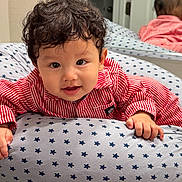Nathan joined the competition — help win amazing prizes! baby, child, pajamas, red_stripes, star_pattern, cushion, mirror, indoor, smile, curly_hair, face, hand, reflection, cute, infant, lying_down, soft_texture, cozy, bright_eyes, portrait