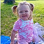 toddler, child, smiling, outdoor, grass, blanket, pigtails, pink_clothing, shorts, playful, happy, sunlight, nature, park, young_child, person, sitting, face, cute, daytime