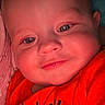 Luca is registered to the contest to win money with this photo: baby, infant, child, portrait, close_up, smiling, eyes, face, red_clothing, shirt, text_on_clothing, indoor, cozy, seated, looking_at_camera, rosy_cheeks, flash_photography, head, baby_outfit, family_photo