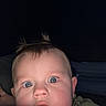 Luca is registered to the contest to win money with this photo: baby, infant, child, face, portrait, wide_eyes, blue_eyes, surprised, close_up, camouflage, clothing, hair, tuft, indoor, dim_lighting, flash, blanket, person, camera, funny_expression