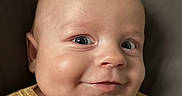 Luca joined the competition — help win amazing prizes! baby, infant, child, portrait, smiling, happy, face, eyes, cheeks, close_up, blanket, yellow_clothing, striped_clothing, couch, indoor, home, cozy, head, photography, adorable