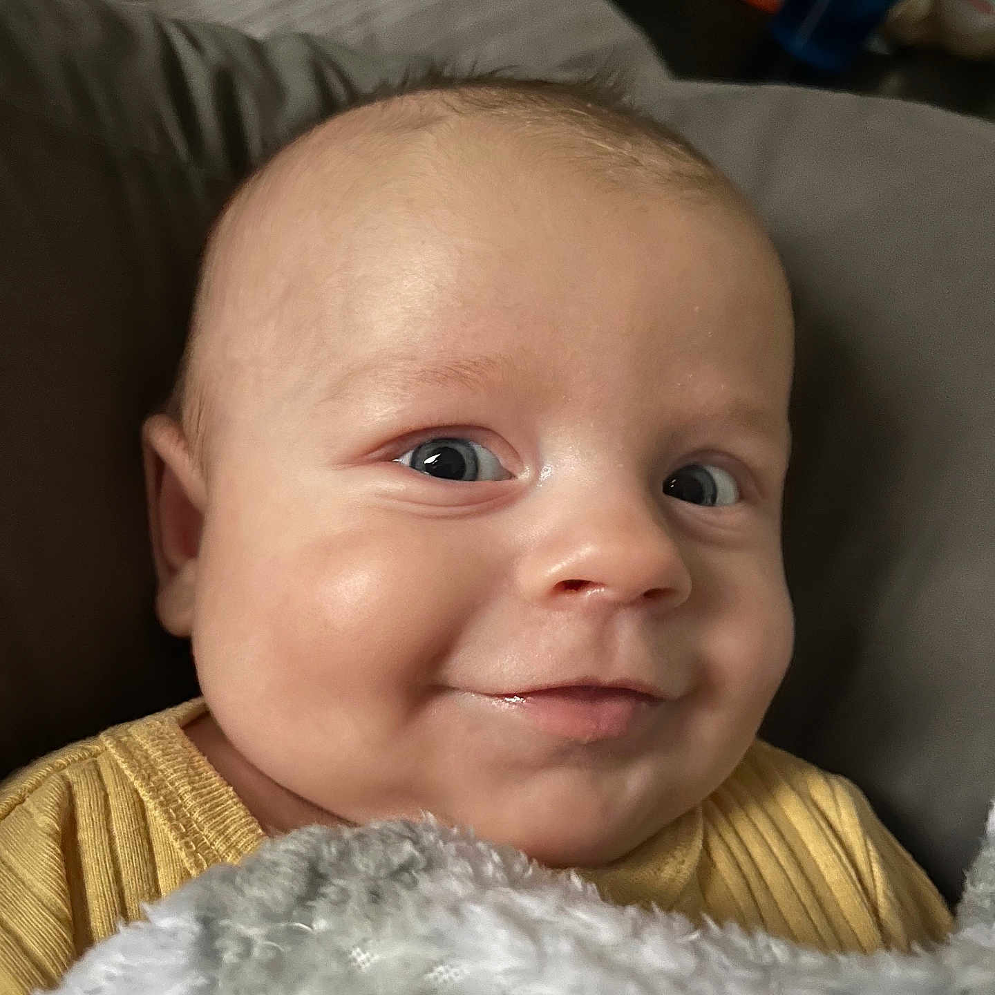 Luca joined the competition — help win amazing prizes! baby, infant, child, portrait, smiling, happy, face, eyes, cheeks, close_up, blanket, yellow_clothing, striped_clothing, couch, indoor, home, cozy, head, photography, adorable