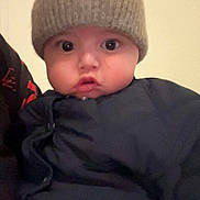 Mallo participe au concours pour gagner de l'argent avec cette photo : baby, child, face, hat, knit_hat, jacket, clothing, wide_eyes, portrait, indoor, cute, infant, young_child, expression, looking, person, headwear, warm_clothing, closeup, soft_lighting