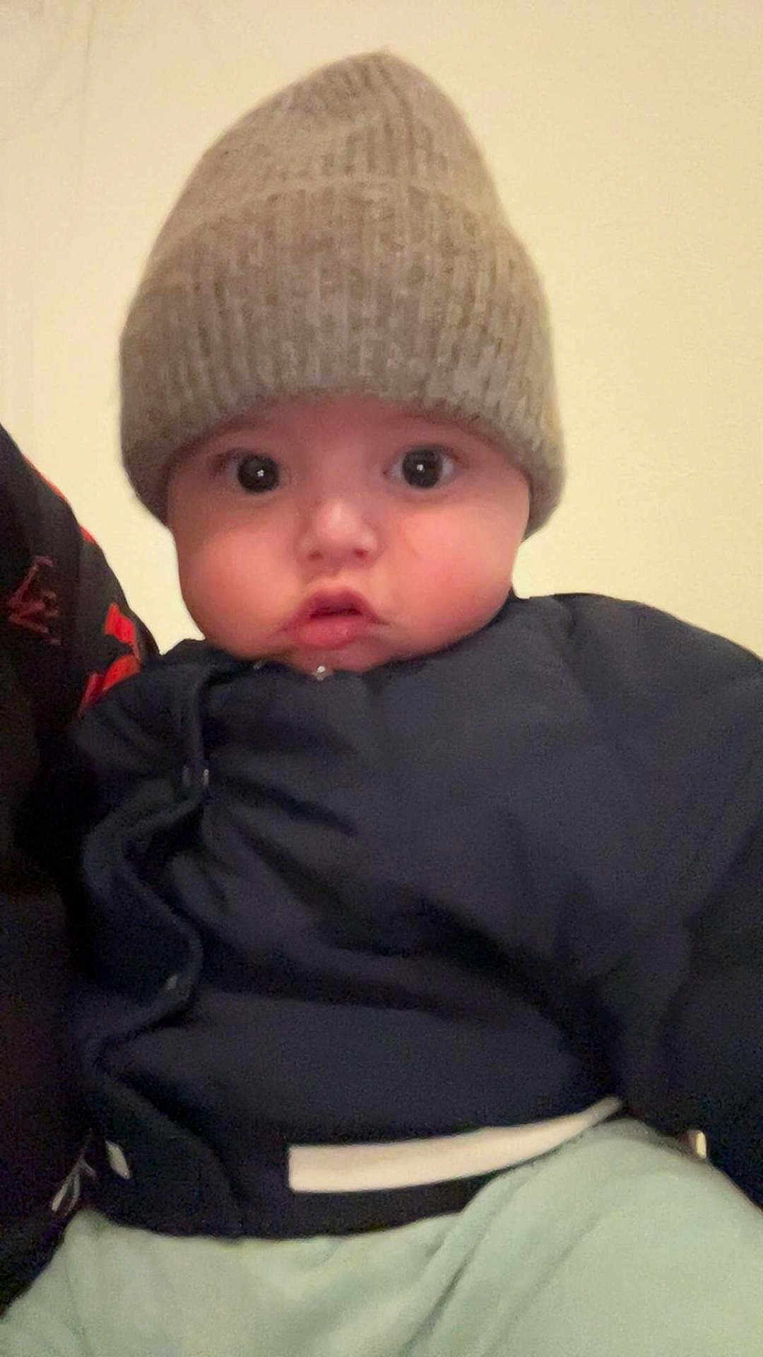 Mallo participe au concours pour gagner de l'argent avec cette photo : baby, child, face, hat, knit_hat, jacket, clothing, wide_eyes, portrait, indoor, cute, infant, young_child, expression, looking, person, headwear, warm_clothing, closeup, soft_lighting