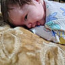 baby, child, infant, blanket, clothing, cute, face, head, lying_down, patterned_blanket, onesie, colorful, soft_texture, portrait, sleepwear, smile, young_child, indoor, closeup, skin