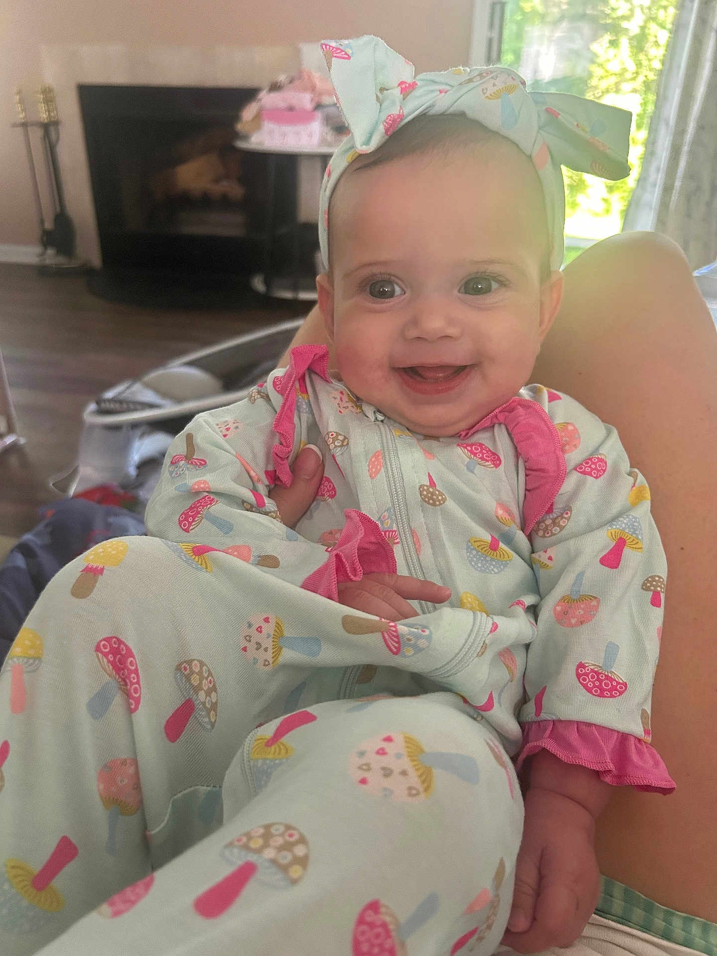Riley joined the competition — help win amazing prizes! baby, smiling, headband, onesie, mushroom_pattern, infant, happy, indoor, living_room, fireplace, window, natural_light, person, clothing, child, cute, sitting, human, portrait, cozy