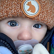 Noé participe au concours pour gagner de l'argent avec cette photo : baby, close_up, face, blue_eyes, pacifier, knitted_hat, bear_patch, winter_clothing, jacket, blanket, cute, child, infant, warm, soft_texture, portrait, young_child, cozy, outdoor_gear, expression