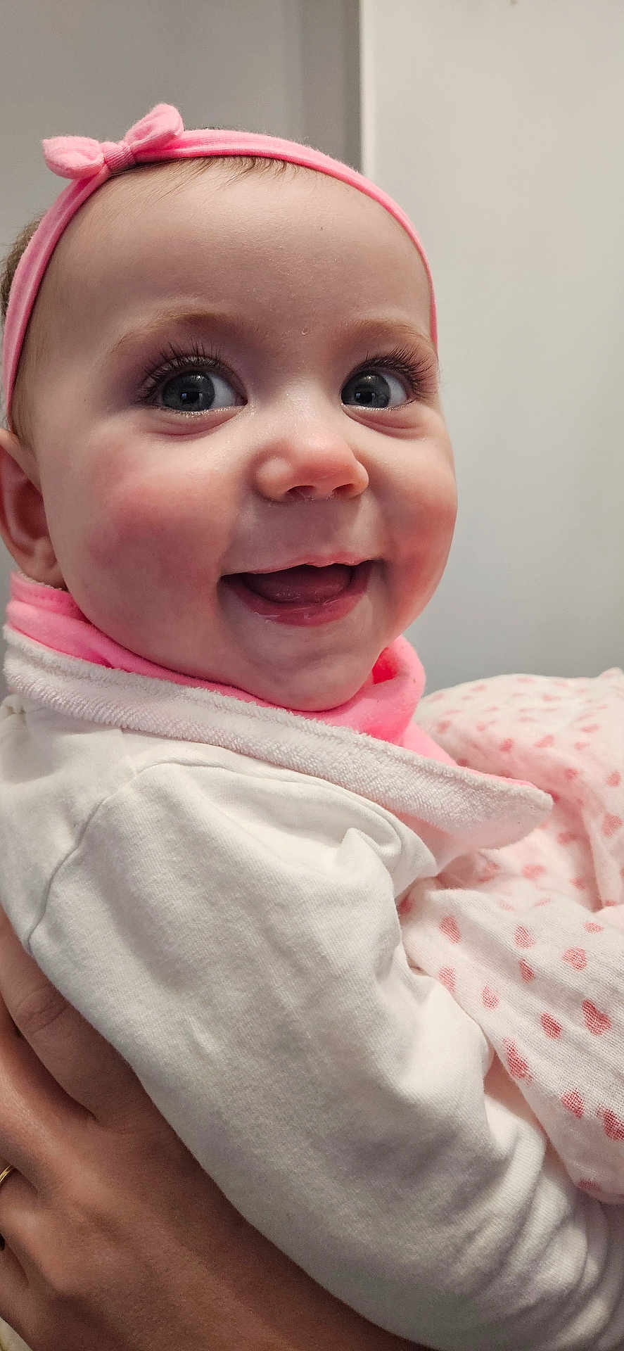 Cléa a rejoint le concours — aidez-le/la à gagner de superbes lots ! baby, infant, smiling, headband, pink, blanket, bib, hand, eyes, eyelashes, cheeks, close_up, portrait, holding, parent_hand, clothing, rosy_cheeks, adorable, indoor, happy
