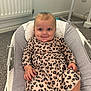 baby, infant, smile, face, blue_eyes, leopard_print, dress, baby_rocker, indoor, carpet, radiator, hand, legs, cute, child, person, happy, seated, clothing, home