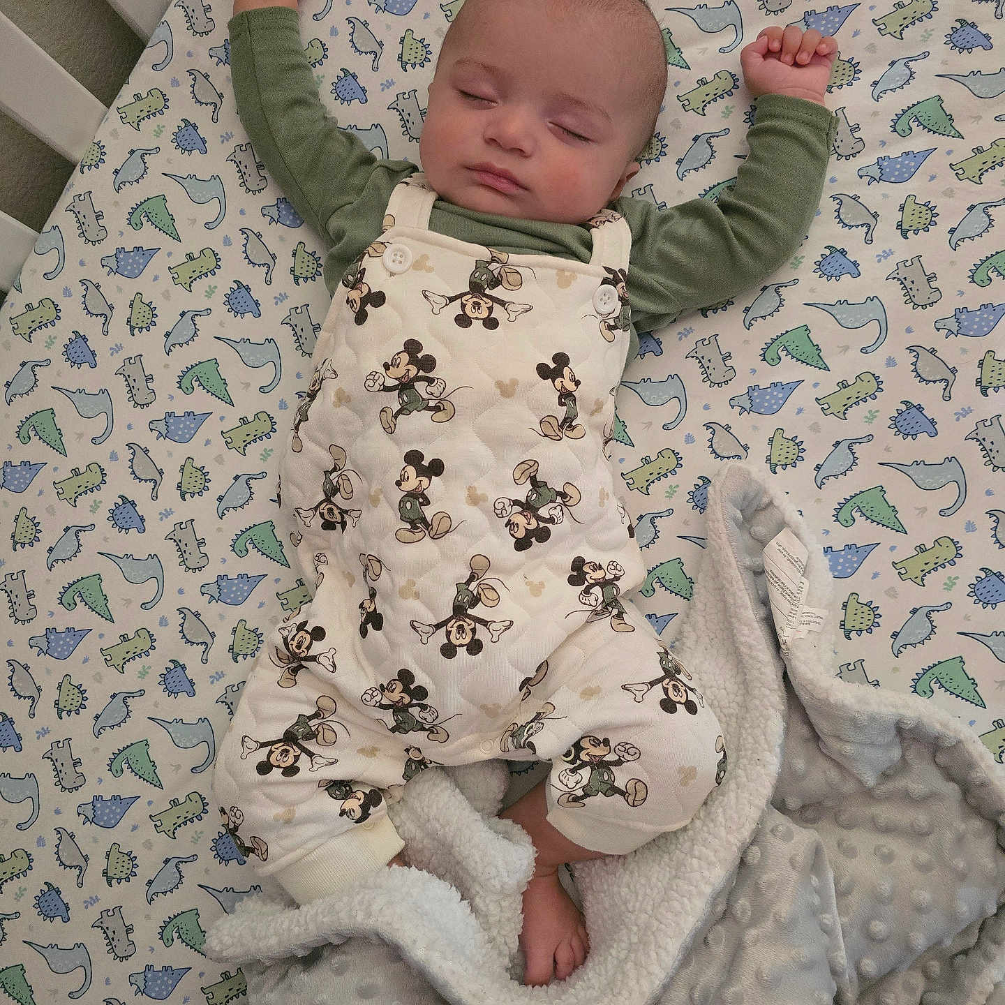 Onofre is registered to the contest to win money with this photo: baby, bed, blanket, child, cozy, crib, cute, dinosaur_pattern, footwear, indoor, infant, mickey_mouse, overalls, pajamas, peaceful, resting, sleeping, sleepwear, soft, toddler