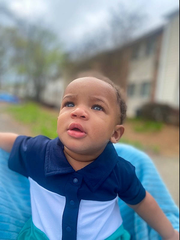 August is registered to the contest to win money with this photo: baby, baby_toddler_clothing, child, electric_blue, fun, gesture, grass, happy, laugh, leisure, people, person, personal_protective_equipment, recreation, sitting, sleeve, smile, t_shirt, toddler, tree