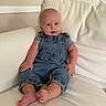 baby, barefoot, blue_eyes, casual_clothing, child, couch, cozy, curious, cute, denim_overalls, drool, furniture, home_interior, infant, living_room, relaxed, seated, smiling, soft_lighting, striped_shirt