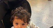 Wael a rejoint le concours — aidez-le/la à gagner de superbes lots ! baby, child, stroller, curly_hair, indoor, public_space, people, floor, luggage, seated, walking, casual_clothing, shopping_bag, stairs, advertisement, helmet, person, waiting, urban, travel