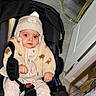 Wael participe au concours pour gagner de l'argent avec cette photo : baby, car_seat, indoor, hat, knitwear, jacket, socks, floor, chair, golden_legs, tile_floor, person, child, cute, warm_clothing, pom_pom, curious, seated, black, beige