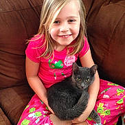 Blue is registered to the contest to win money with this photo: child, girl, cat, pet, pajamas, pink_clothing, gray_cat, couch, indoor, smiling, sitting, holding, furry_pet, cute, cozy, happy, young, animal, home, relaxed