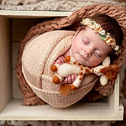 Adelaide is registered to the contest to win money with this photo: baby, blanket, closeup, cozy, cute, flower, giraffe, headband, indoor, infant, knit, newborn, peaceful, portrait, resting, sleeping, soft, toy, wooden_box, wrapped
