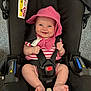 baby, car_seat, smile, pink_hat, pink_striped_clothing, infant, seat_belt, happy, child, foot, hand, indoor, fabric, black_car_seat, headwear, person, cute, safety_harness, cheeks, straps