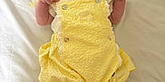 Vaughn is registered to the contest to win money with this photo: baby, infant, yellow_clothing, headband, bow, sock, cute, lying_down, portrait, child, soft_light, white_background, newborn, small_hands, smiling, adorable, indoors, fashion, happy, closeup