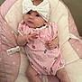Vaughn is registered to the contest to win money with this photo: baby, infant, headband, bow, pink, striped_clothing, socks, cushion, seat, soft, cute, child, newborn, indoor, portrait, looking, comfortable, small_hands, legs, expression