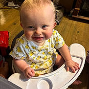 Deelylah is registered to the contest to win money with this photo: baby, child, cute, eyes, face, floor, food_crumbs, foot, furniture, hand, happy, high_chair, indoor, onesie, person, smile, snack, tongue, wooden_floor, yellow_flower_pattern