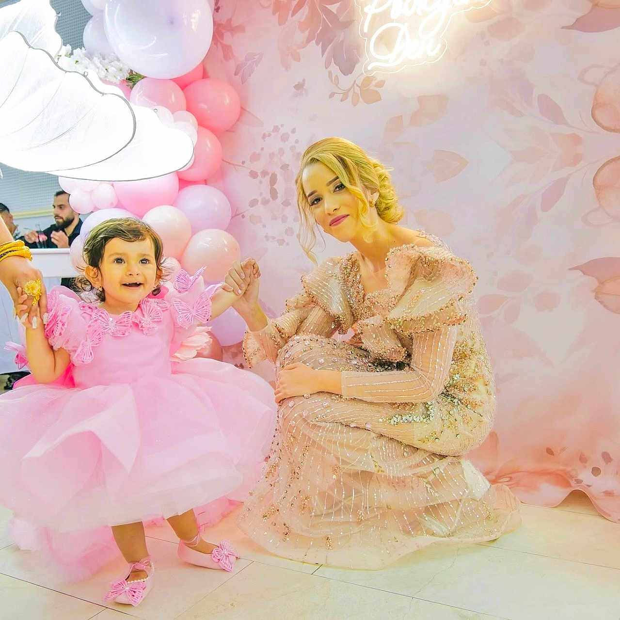 Veska is registered to the contest to win money with this photo: balloons, butterfly, celebration, child, curly_hair, decorations, dress, event, floor, flowers, happy, holding_hands, indoor, light, party, person, pink_dress, smiling, toddler, woman