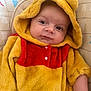 baby, child, comfort, cute, ears, expression, eyes, face, fuzzy_clothing, hood, indoor, infant, onesie, pattern, person, portrait, red, seat, sitting, yellow