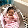 baby, infant, smile, pink_clothing, baby_seat, curtain, floor_tiles, indoor, cushion, happy, hands, feet, face, person, cozy, pattern, butterfly, head, cheerful, child
