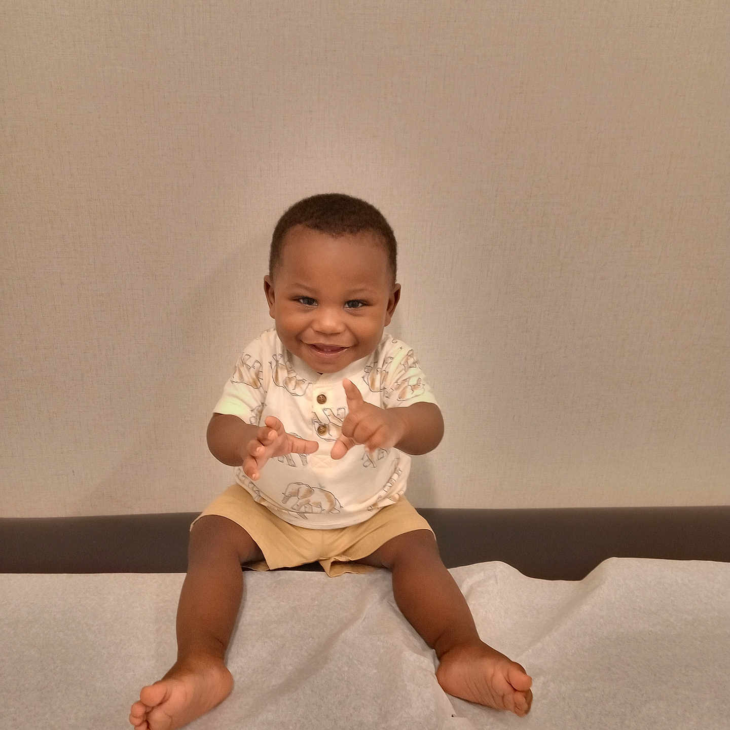 Ke'Vontae is registered to the contest to win money with this photo: baby, barefoot, child, cute, furniture, hands, happy, indoor, medical_table, paper_sheet, person, playful, portrait, shirt, shorts, sitting, smiling, toddler, wall, young_child