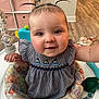 baby, child, pigtails, smiling, indoor, baby_seat, animal_print, cute, happy, infant, clothing, furniture, flooring, storage, toy, person, face, portrait, home, wood_floor