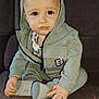 toddler, child, hoodie, green_clothing, socks, indoor, sofa, brown_sofa, seated, baby, cute, curious, small_hands, face, portrait, young_child, casual_wear, cozy, home, expression