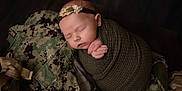 Sawyer is registered to the contest to win money with this photo: newborn, baby, sleeping, wrapped, headband, flower, olive_green, camouflage, military_uniform, texture, peaceful, infant, portrait, soft_lighting, closeup, hands, cute, resting, fabric, indoor
