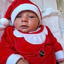 baby, blanket, child, christmas, cozy, cute, face, festive, hand, holiday, indoor, infant, portrait, red_clothing, santa_hat, smile, soft_texture, warm, white_trim, young