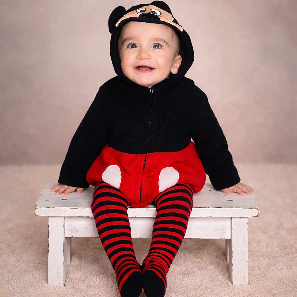 Leïo a rejoint le concours — aidez-le/la à gagner de superbes lots ! baby, bench, black, carpet, child, clothing, costume, cute, happy, hoodie, indoor, mickey_mouse, person, portrait, red, sitting, smiling, striped_tights, studio, young_child