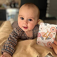 Lou participe au concours pour gagner de l'argent avec cette photo : baby, infant, child, portrait, blanket, milestone_card, plaid_clothing, large_eyes, smile, hand, cheek, indoors, cozy, bokeh, shallow_depth_of_field, card, skin, cute, lying_down, nursery
