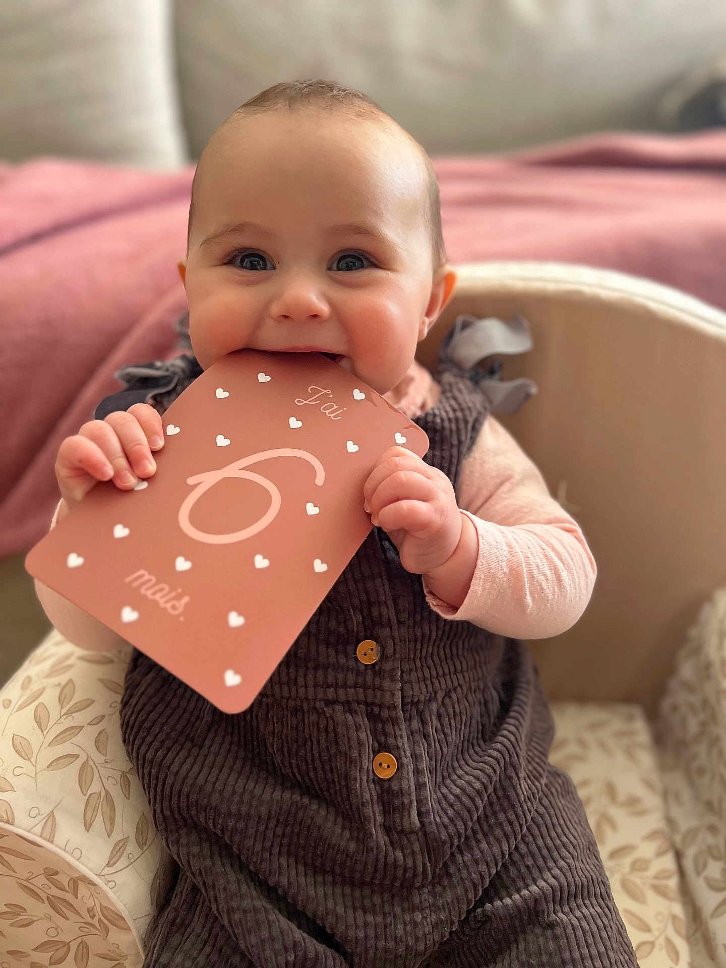 Lou participe au concours pour gagner de l'argent avec cette photo : baby, infant, child, smiling, teething, milestone_card, biting, hands, eyes, cheeks, overalls, corduroy, buttons, blanket, sofa, indoor, portrait, close_up, bokeh, cute