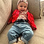 Lou participe au concours pour gagner de l'argent avec cette photo : baby, infant, smile, headband, floral, cardigan, red_clothing, jeans, socks, couch, cushion, living_room, portrait, happy, cute, face, seated, hands, textile, home