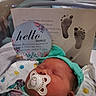 newborn, baby, pacifier, headband, hospital, bassinet, blanket, footprints, birth_card, sleeping, infant, cute, resting, baby_clothes, hospital_room, celebration, portrait, child, peaceful, indoors