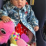 baby, child, car_seat, plush_toy, seahorse, jacket, denim, flower_pattern, polka_dots, red_skirt, cute, serious_expression, indoor, warning_label, seatbelt, sitting, person, infant, soft_toy, colorful