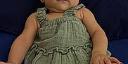 Analia Sucre is registered to the contest to win money with this photo: baby, infant, child, green_clothing, cushion, navy_blue, portrait, relaxing, indoor, cute, smiling, person, furniture, skin, hand, foot, earrings, shorts, top, bracelet