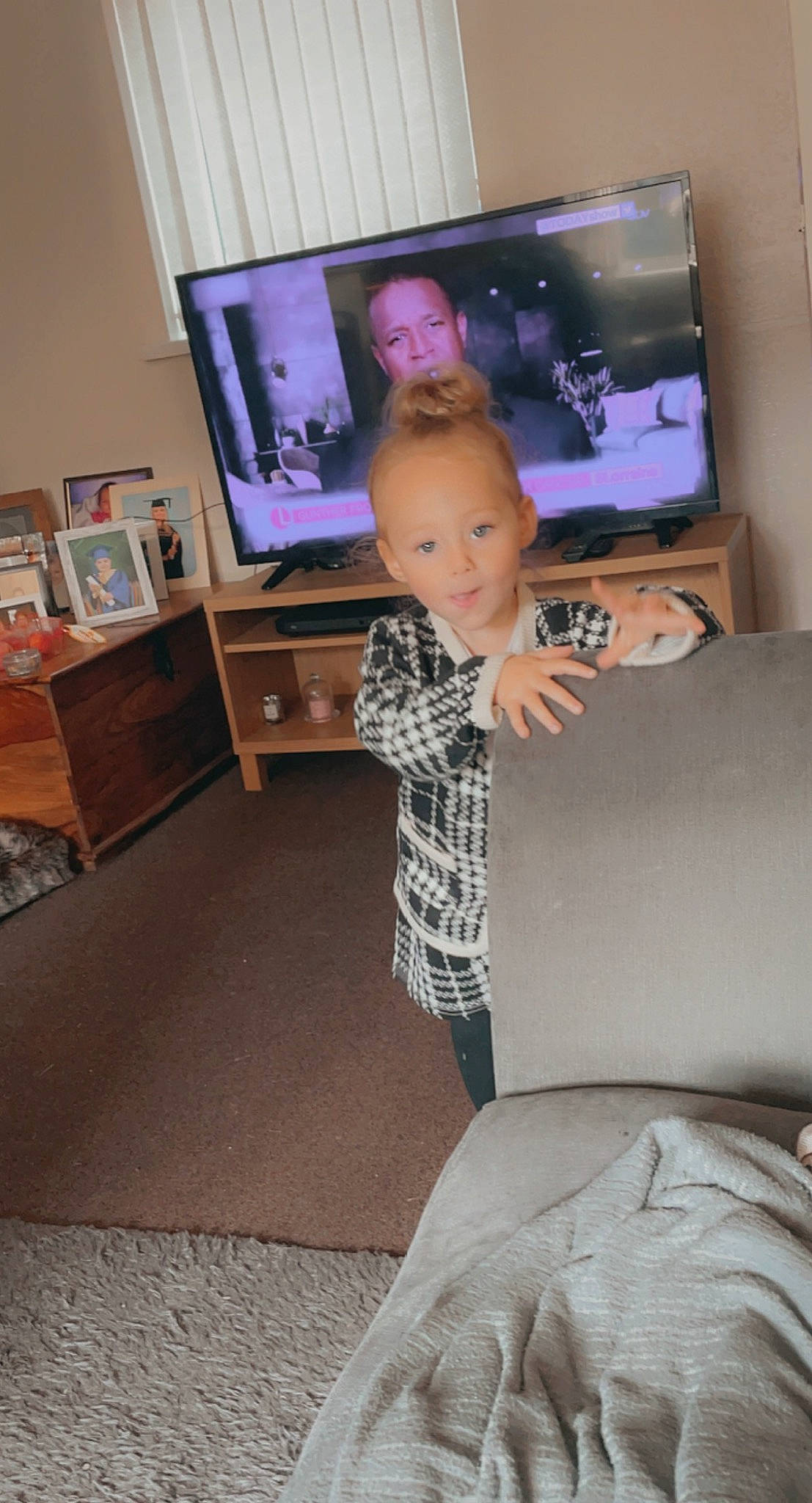 Bethany joined the competition — help win amazing prizes! child, comfort, couch, electronic_device, floor, flooring, fun, furniture, gadget, hairstyle, hardwood, home_appliance, human_leg, living_room, person, shoulder, standing, television, television_set, toddler