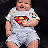 baby, black_leather_chair, button, child, curly_hair, cute, furniture, happy, indoor, infant, one_person, overalls, portrait, shorts, sitting, skin, smiling, striped_clothing, superman_logo, white_tshirt